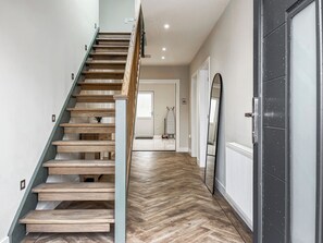 A staircase with wooden steps and a metal handrail, leading to a room with a white door and a mirror on the wall. - Barncroft Cottage - UK51692 (High Seaton, near Workington)