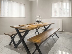 A dining table with benches, a vase of flowers, and a radiator in the background. - Barncroft Cottage - UK51692 (High Seaton, near Workington)