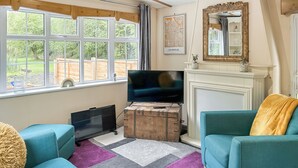 A living room with a large window, a television, a fireplace, and two sofas. - Station House Retreat (Royston)