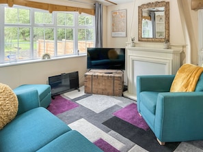 Ein Wohnzimmer mit großem Fenster, Fernseher, Kamin und zwei Sofas.
