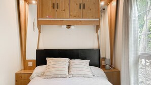 A bed with two pillows, a bedside lamp, and a window with curtains. - Station House Retreat (Royston)