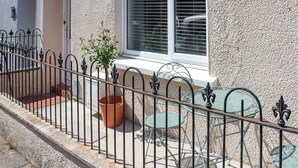A building with a white exterior, a window with blinds, a metal fence, and outdoor seating with chairs and tables. - Platform 1 - Uk51994 (Haverfordwest)