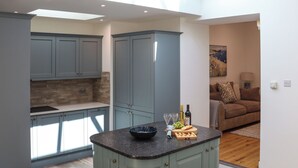A kitchen with grey cabinets, a central island, and a dining area with a brown sofa. - Platform 1 - Uk51994 (Haverfordwest)