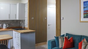 A compact living space with a kitchenette, a sofa, and a wooden partition. - Platform 2 - UK51996 (Haverfordwest)
