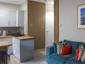 A compact living space with a kitchenette, a sofa, and a wooden partition. - Platform 2 - UK51996 (Haverfordwest)