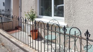 A building with a white exterior, a window with blinds, a metal fence, and outdoor furniture. - Platform 2 - UK51996 (Haverfordwest)