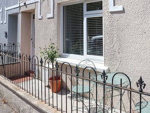 A building with a white exterior, a window with blinds, a metal fence, and outdoor furniture. - Platform 2 - UK51996 (Haverfordwest)