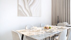 Een eetruimte met een marmeren tafel, stoelen, een schaal met fruit en een modern abstract schilderij.