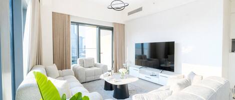 A modern living room with a large flat-screen TV, a sectional sofa, and a coffee table.