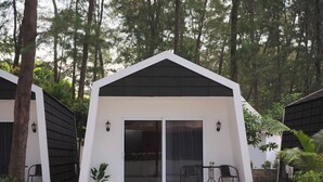 A modern, single-story building with a white exterior and black roof, surrounded by trees.