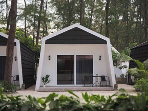 A modern, single-story building with a white exterior and black roof, surrounded by trees.