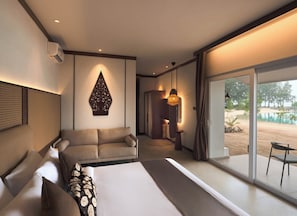 Ett modernt hotellrum med en stor sÀng, en soffa, en matplats och utsikt över en strand.