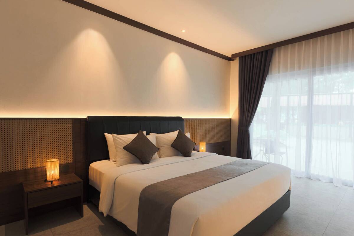 Ein modernes Hotelzimmer mit einem großen Bett, Nachttischen und Blick ins Freie.