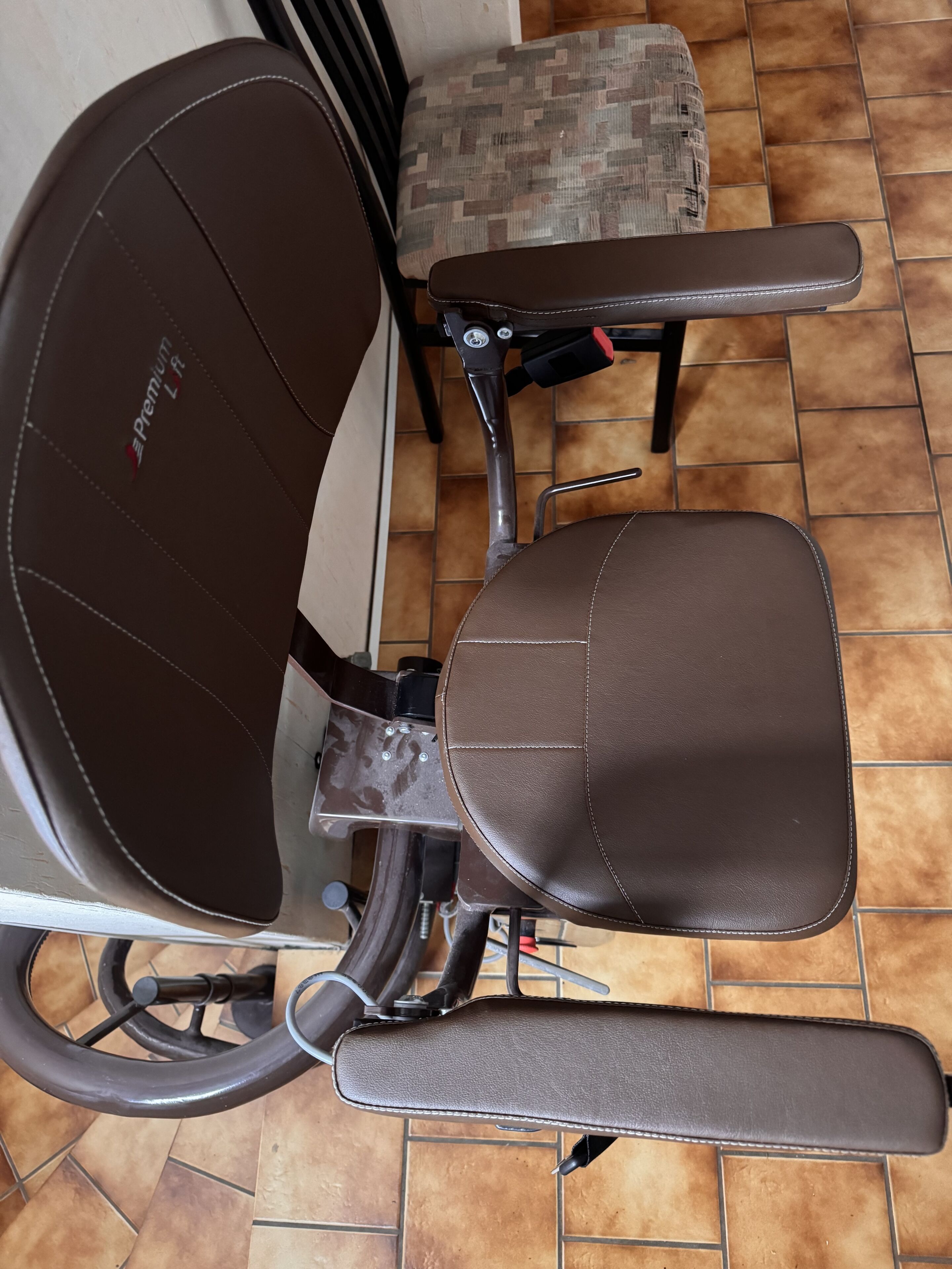 Une chaise dotée d’un siège et d’un dossier rembourrés, d’une structure en métal et d’un repose-pieds.