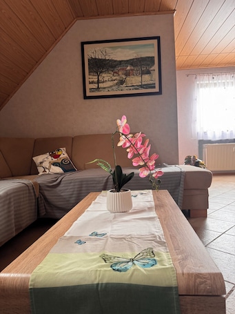 A cozy room with a wooden ceiling, a painting on the wall, a sofa, a table with a butterfly tablecloth, and a potted orchid.. Quiet designer apartment with whirlpool tub, steam shower, and nature