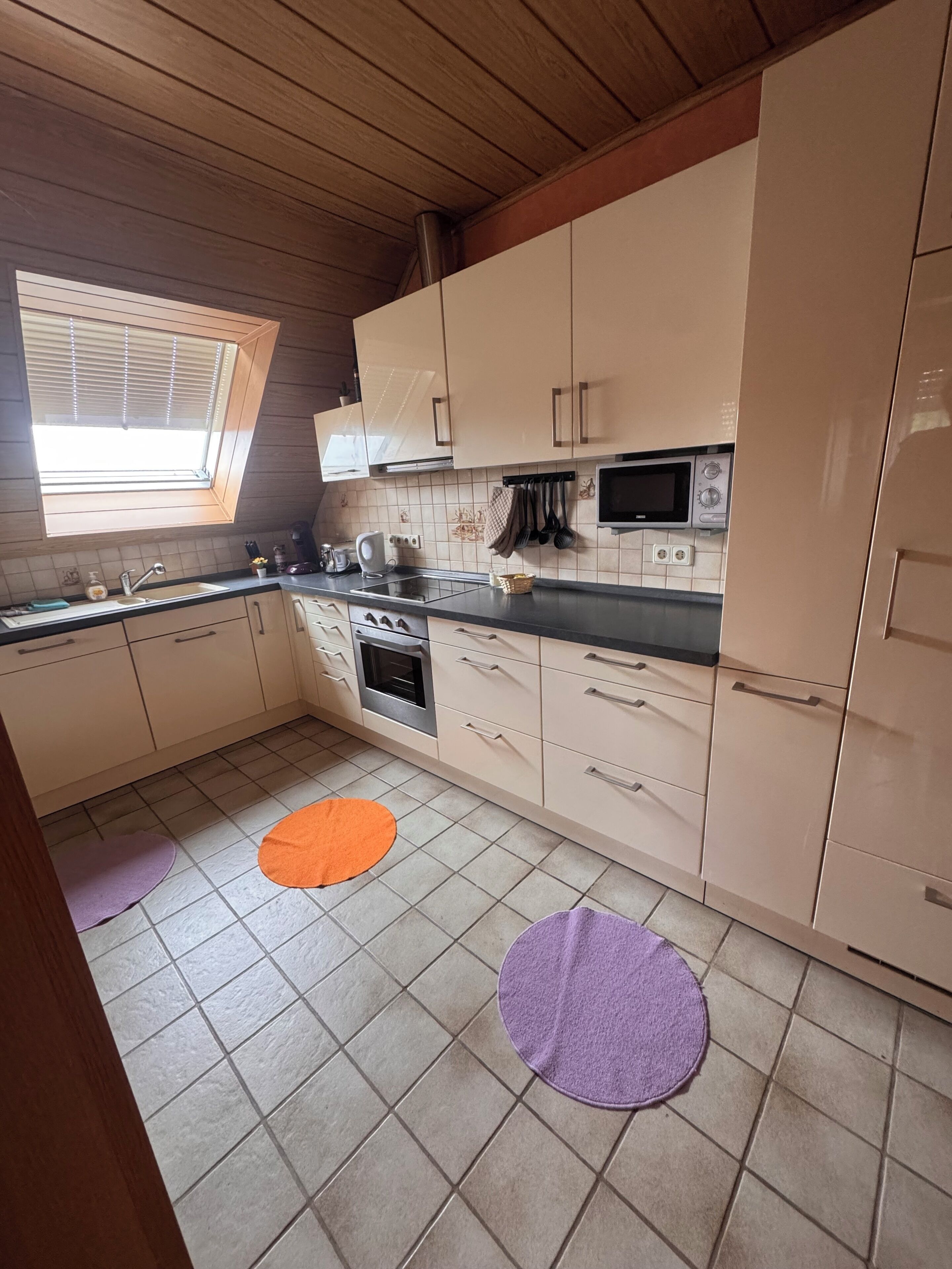 Eine Küche mit Fenster, Mikrowelle und Herd.