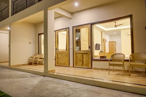 A modern hotel with a spacious outdoor area, wooden doors, and wicker chairs. - Cygnett Collection Jim Corbett (Ramnagar)