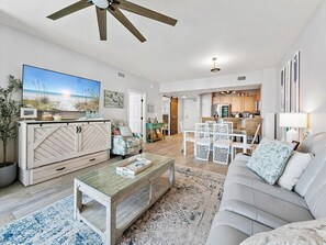 A spacious living room with a large TV, a ceiling fan, and a dining area with a table and chairs. - Spacious 3-bedroom apartment in gorgeous Destin with AC (Destin)