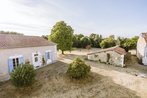 Un paysage rural avec des bâtiments traditionnels, un ciel dégagé et un chemin de terre.