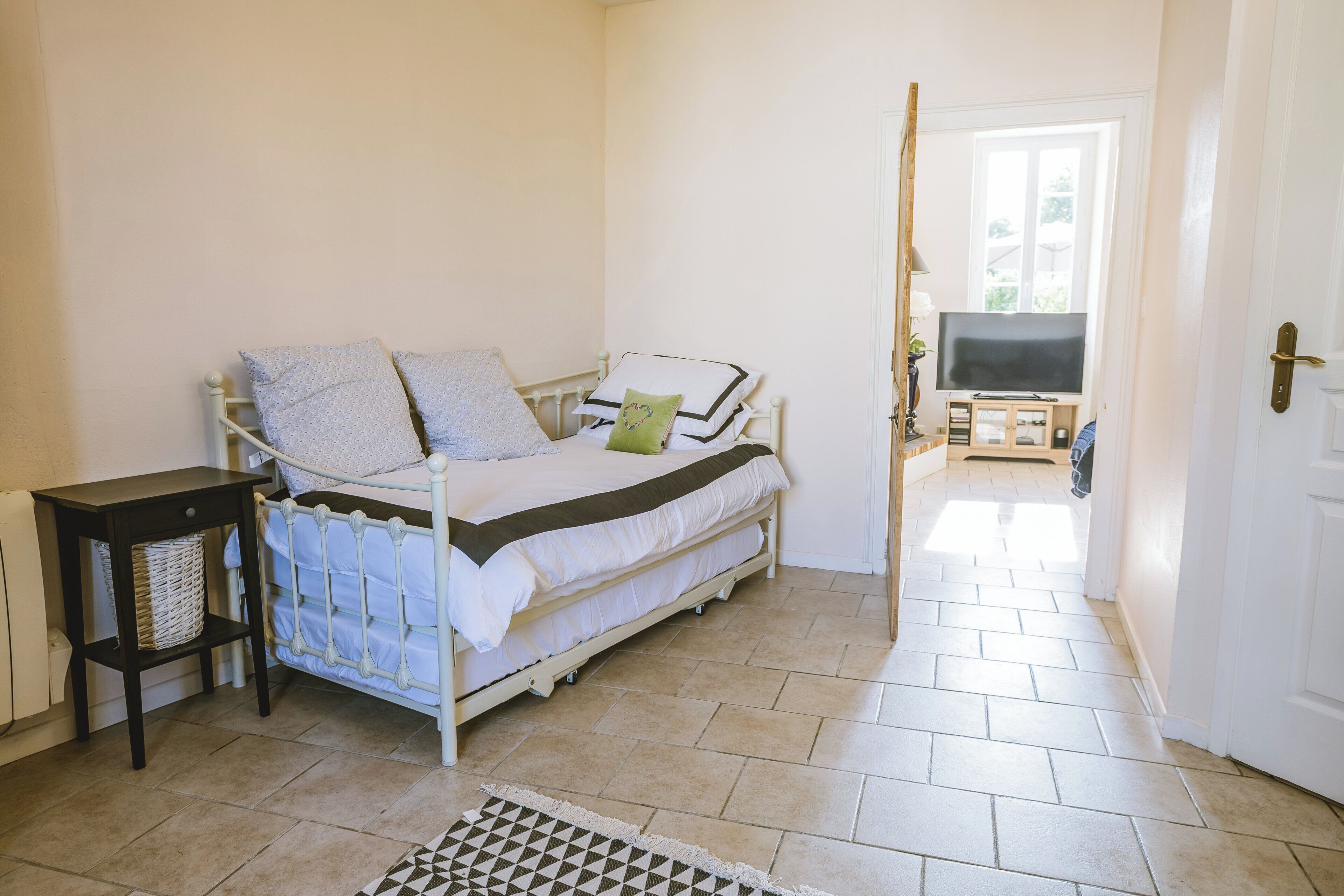 Ein Schlafzimmer mit Bett, Nachttisch, TV-Schrank und Blick ins Freie.
