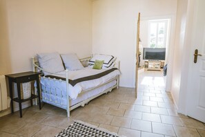 Une chambre à coucher comprenant un lit, une table de chevet, un meuble pour la télévision et donnant sur l’extérieur.