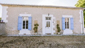 A two-story building with a stone facade, white door, and blue shutters. - Annie's Cottage 2Ch fully equipped house (Ribérac)