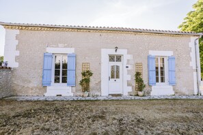 Ein zweistöckiges Gebäude mit Naturstein-Fassade, einer weißen Tür und blauen Fensterläden.