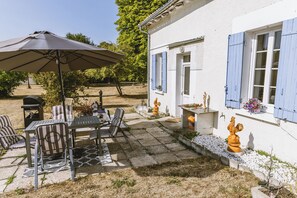 Une terrasse avec des meubles d’extérieur, une table et un parasol.
