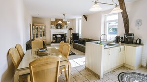 A kitchen with a dining area, a fireplace, and a large window. - Annie's Cottage 2Ch fully equipped house (Ribérac)