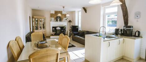A kitchen with a dining area, a fireplace, and a large window.