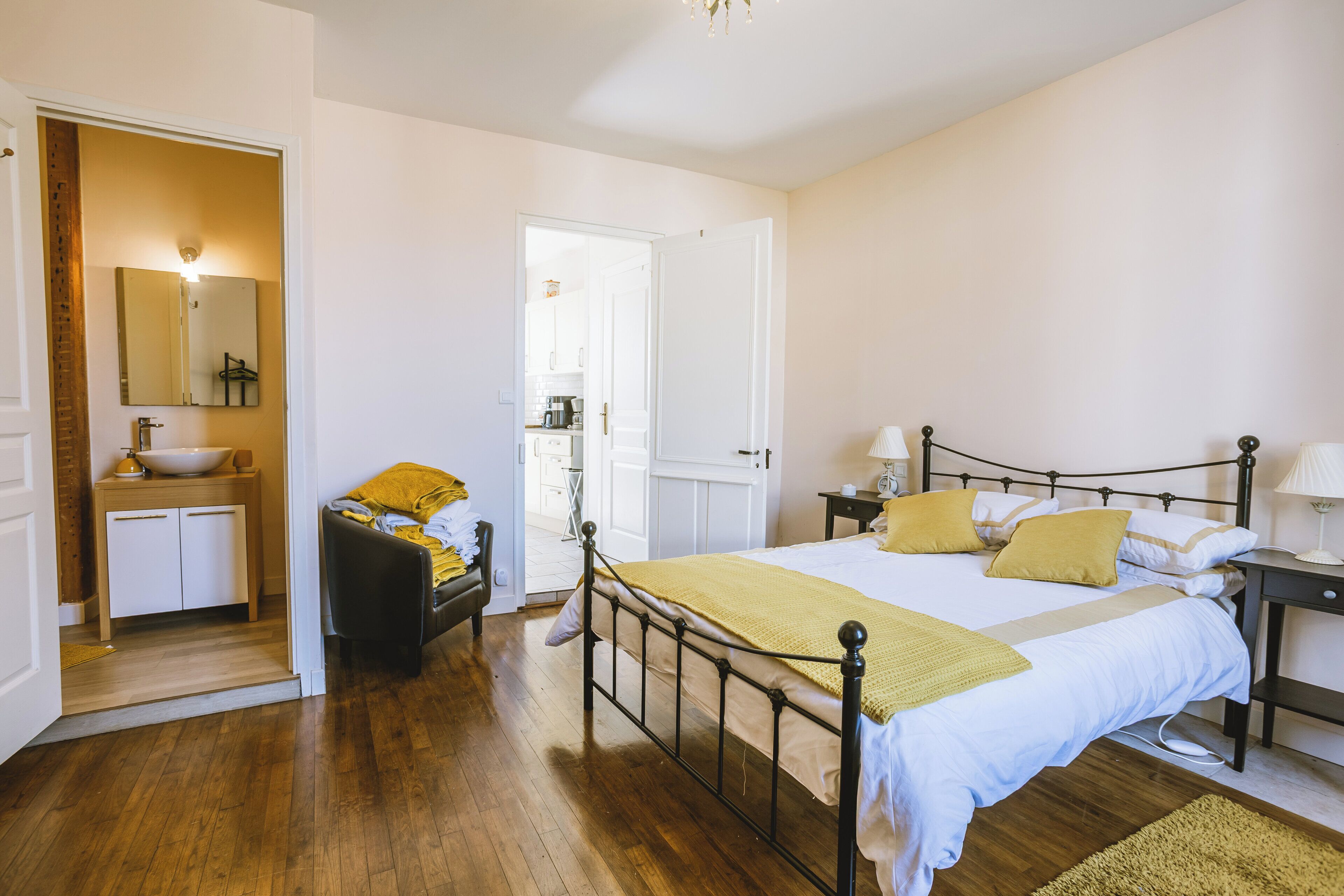 A bedroom with a bed, bedside tables, a mirror, and a bathroom with a sink and mirror.