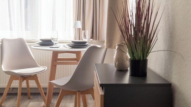 A dining area with a table set for two, chairs, a potted plant, and a lamp. - Studio no. 3 newly furnished modern vacation in Wöhrden near Büsum (Wöhrden)