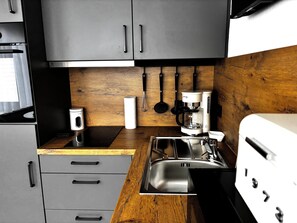 Una cocina moderna con armarios grises, encimera de madera, cafetera y lavabo.