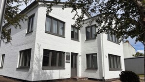 A two-story white brick building with multiple windows and a small front porch. - Studio no. 3 newly furnished modern vacation in Wöhrden near Büsum (Wöhrden)