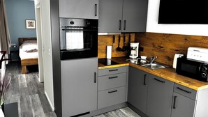 A compact kitchen with grey cabinets, a wooden countertop, a built-in oven, a coffee maker, and a microwave. - Studio no. 3 newly furnished modern vacation in Wöhrden near Büsum (Wöhrden)