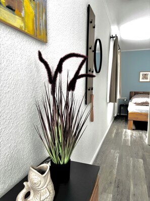A modern room with a bed, a potted plant, and a wall-mounted artwork.