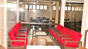 A conference room with a long table and red chairs, glass walls, and a view of the outside. - Hotel Twin Towers (Homa Bay)