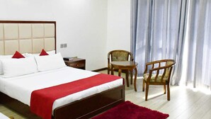 A hotel room with a bed, two chairs, a small table, and a window with curtains. - Hotel Twin Towers (Homa Bay)