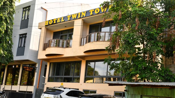 A building with a sign reading 'HOTEL TWIN TOWERS' and two parked cars in front. - Hotel Twin Towers (Homa Bay)