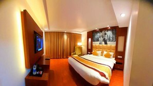 Habitación de hotel con una cama grande, televisor en la pared, escritorio con lámpara y un cuadro en la pared.