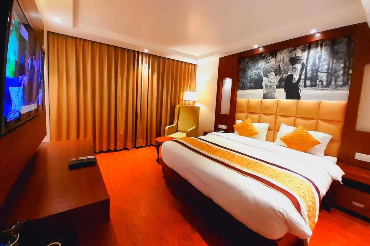 Habitación de hotel con una cama grande, televisión, escritorio con lámpara y una obra de arte en la pared.