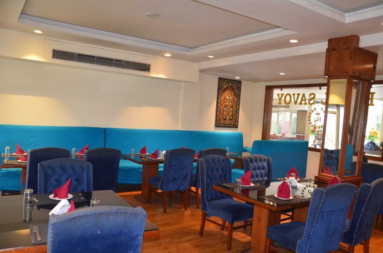 A restaurant with blue upholstered booths, wooden tables, and chairs.