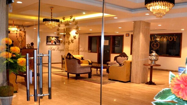 Un vestíbulo de hotel con mostrador de recepción, zona de estar, candelabros y un amplio ventanal con vistas.
