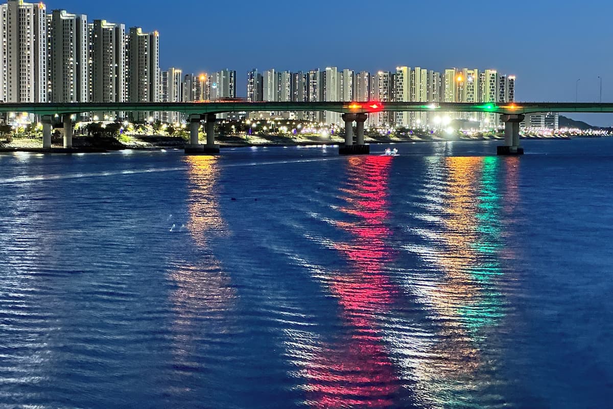 A bridge over water with tall buildings in the background.