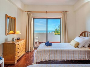 A bedroom with a bed, a dresser, a mirror, and a view of the sea. - Ocean Mood by Interhome (Porches)