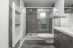 Een moderne badkamer met douche, toilet en wastafel.