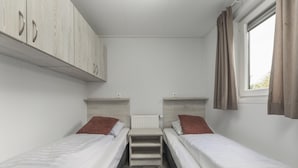 A small, clean room with two single beds, a radiator, and a window with curtains. - Vacation Home with Charming Porch (Zuna)