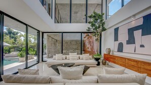 Un interior moderno con un amplio salón, una piscina y un techo alto.