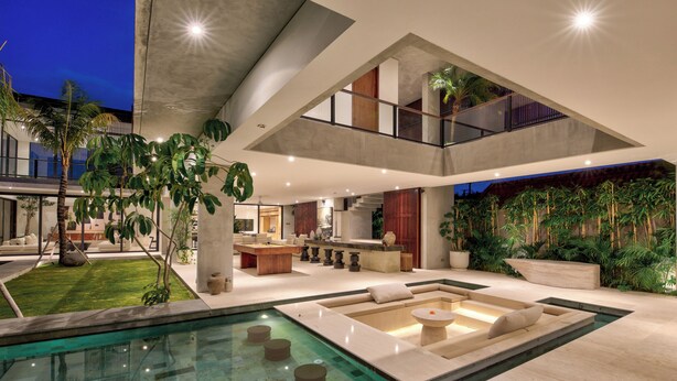 A modern interior with a pool, seating areas, and a staircase. - Tama House (Canggu)
