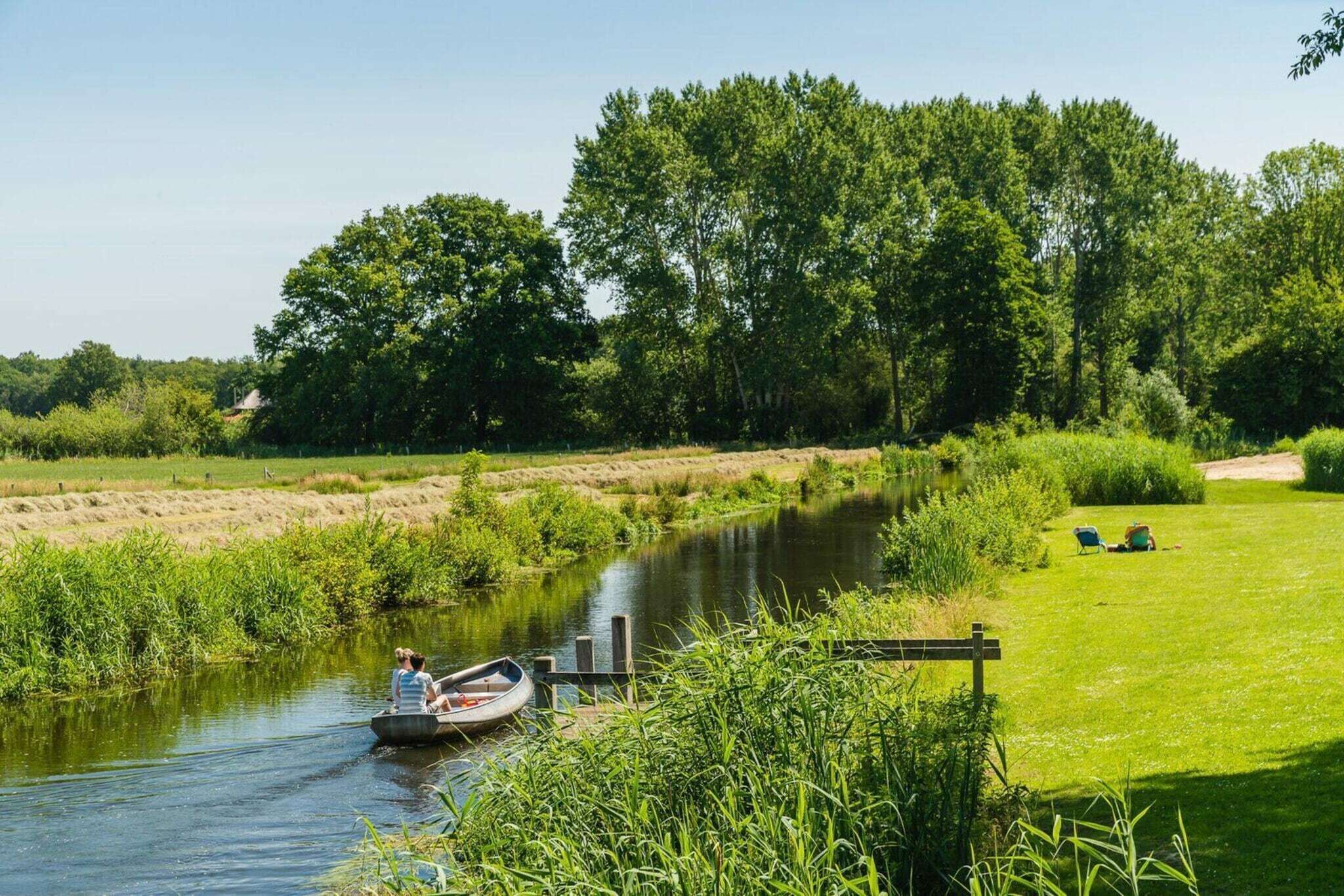 A river with a boat, surrounded by greenery and trees.
